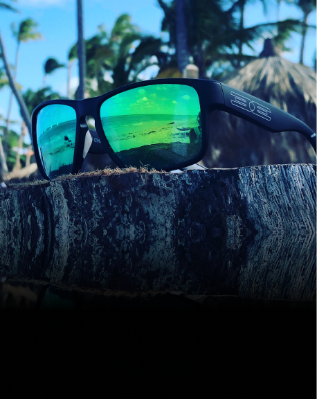 green mirror delta sunglasses laying on top of tree stump
